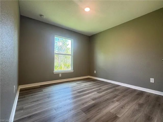 Spare room with a textured wall, a textured ceiling, and dark wood finished floors