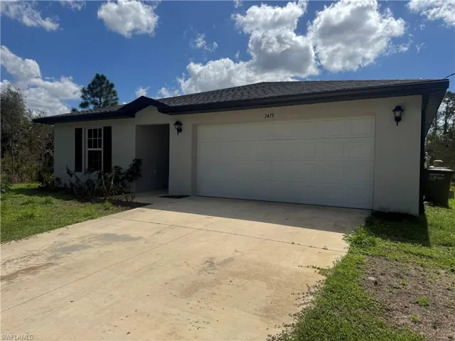 Ranch-style home featuring a garage, concrete driveway, stucco siding, and a front yard