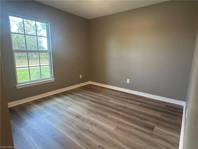 Spare room with baseboards and dark wood finished floors