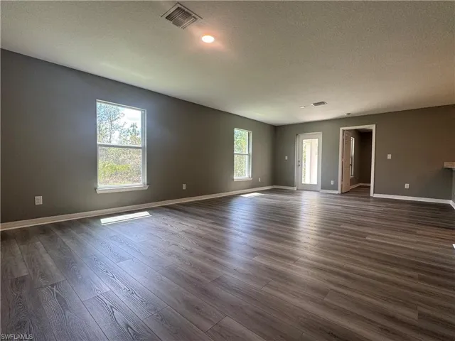 Spare room with a textured ceiling and dark wood-style flooring