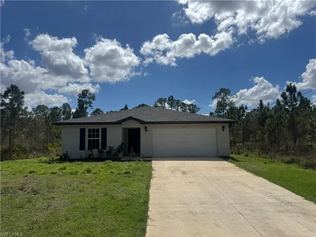 Ranch-style home featuring an attached garage, a front lawn, and concrete driveway
