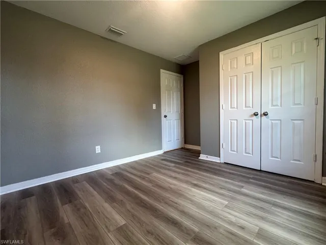 Unfurnished bedroom with wood finished floors and a closet