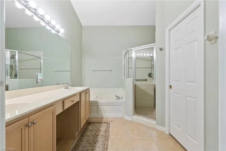 MOVE IN READY Primary Bathroom featuring a shower stall, a garden tub, tile patterned flooring, and double vanity