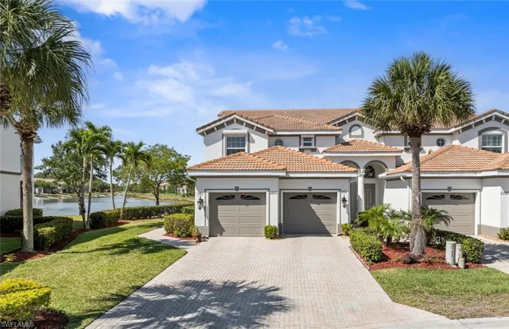 View of front of home featuring a front lawn, a tiled roof, an attached garage, stucco siding, and decorative driveway