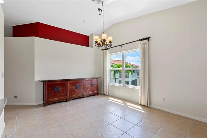 MOVE IN READY Tiled dining area with a chandelier and vaulted ceiling
