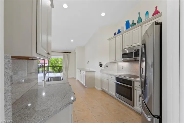 MOVE IN READY Kitchen featuring backsplash, appliances with stainless steel finishes, light tile patterned floors, recessed lighting, and light stone counters