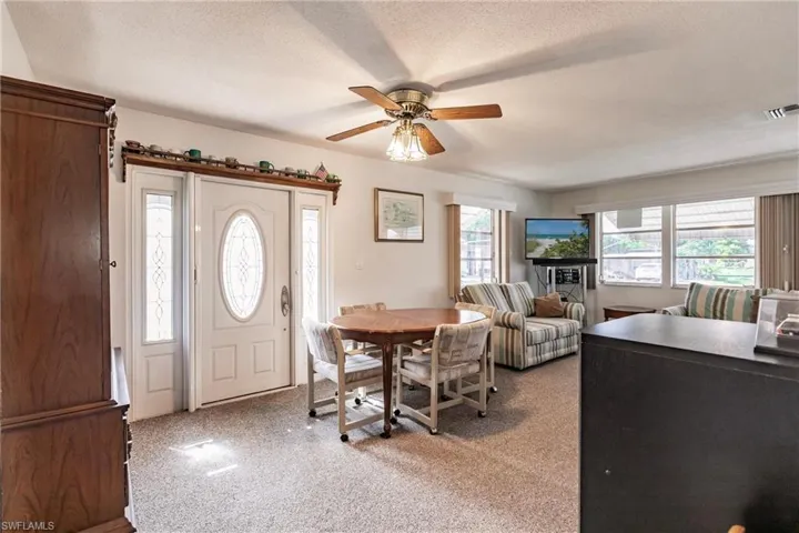 Carpeted entrance foyer featuring ceiling fan and a textured ceiling