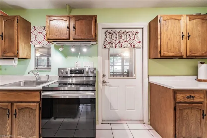 Kitchen with sink, electric stove, and light tile floors