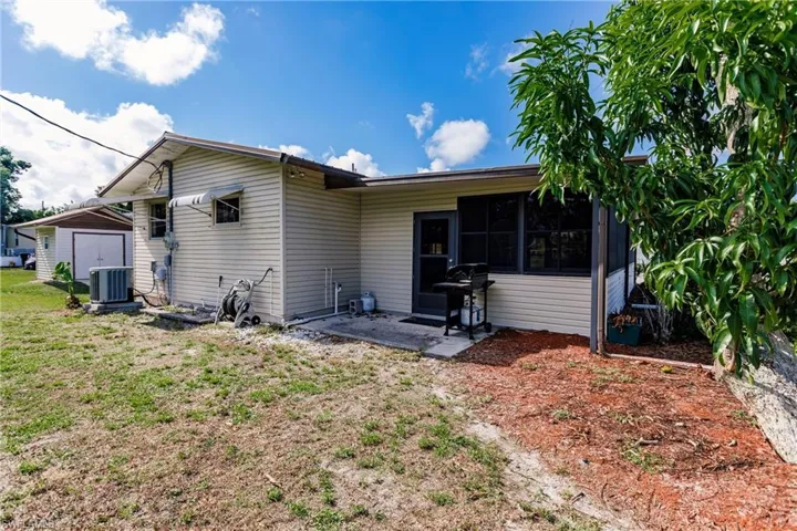 Rear view of property featuring central AC and a yard