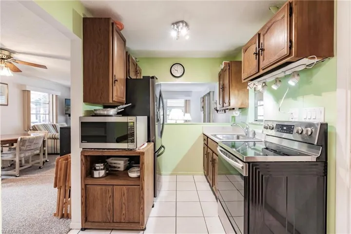 Kitchen featuring ceiling fan, sink, light tile floors, and appliances with stainless steel finishes