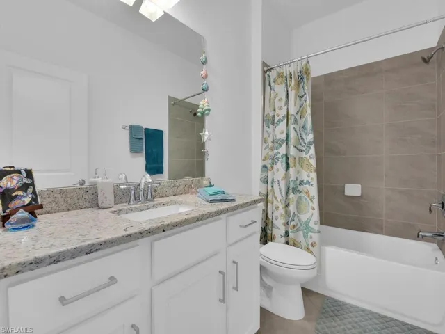 Full bath with vanity, shower / bathtub combination with curtain, and light tile patterned flooring