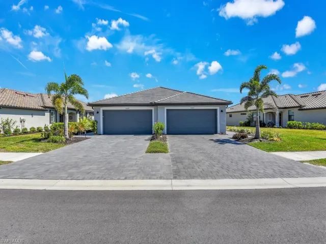 Ranch-style house featuring decorative driveway, stucco siding, a tile roof, a front yard, and a garage