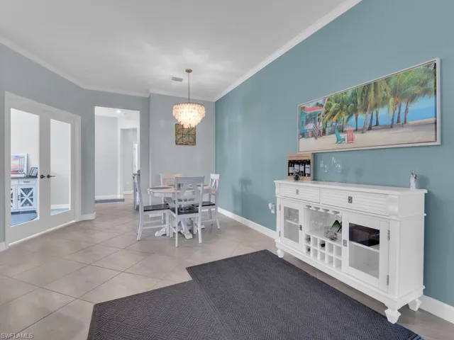 Dining room with crown molding, french doors, hanging lights, and light tile patterned floors