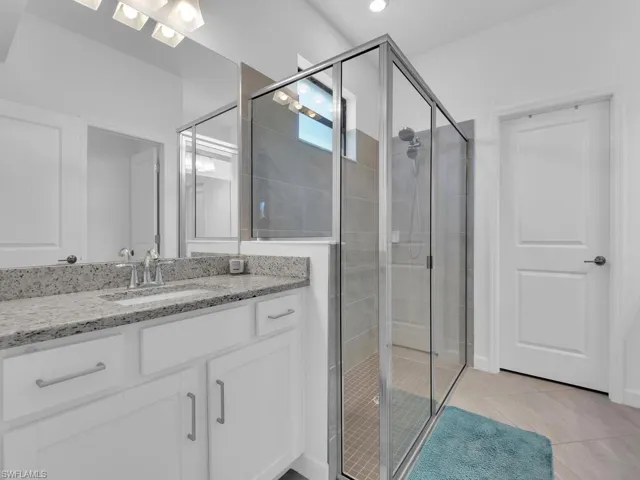 Bathroom featuring a shower stall, vanity, light tile patterned flooring, and recessed lighting