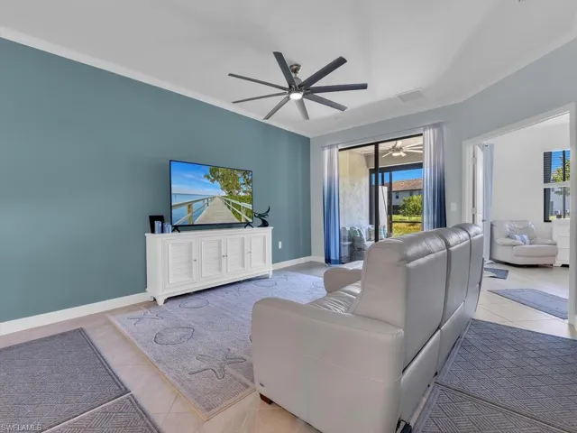 Tiled living area featuring a ceiling fan and ornamental molding