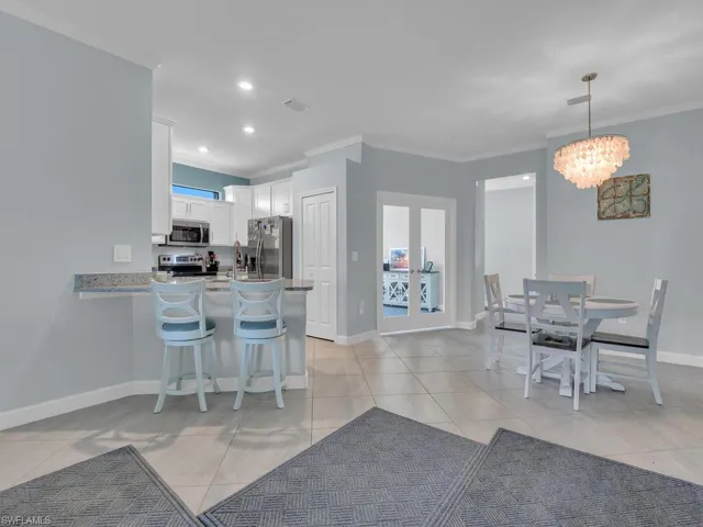 Dining room featuring crown molding, light tile patterned flooring, a chandelier, and french doors
