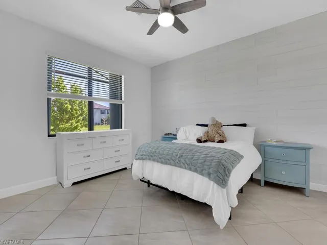 Bedroom with tile walls, ceiling fan, and light tile patterned flooring