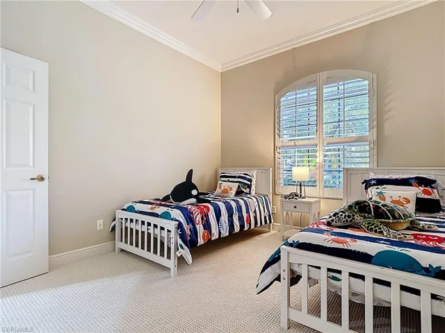 Bedroom with a ceiling fan, newer carpeted floors, and ornamental molding.