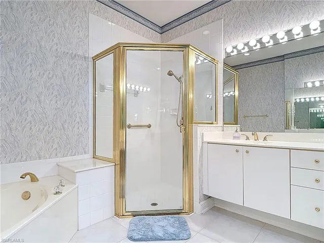 Full bathroom featuring wallpapered walls, a shower stall, a bath, and vanity