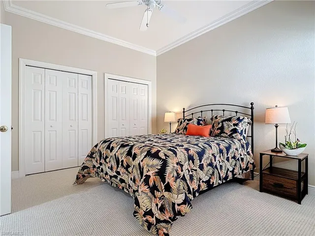 Carpeted bedroom with multiple closets, a ceiling fan, and crown molding