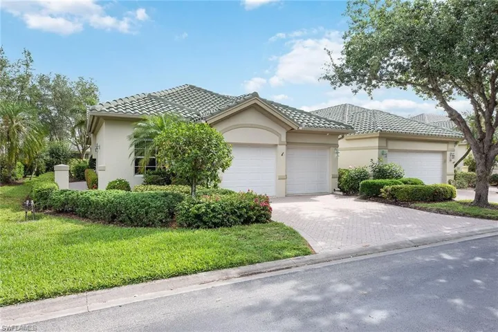 View of front facade with a tiled roof, driveway, and stucco siding