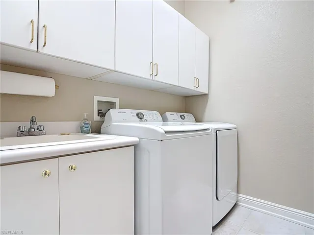 Laundry area with light tile floors,  cabinet space, a sink, and independent washer and dryer
