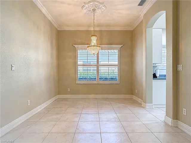 Dining room featuring, light tile patterned flooring, arched walkways, and ornamental molding