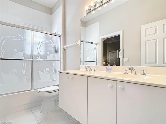 Full bathroom with a sink, toilet, combined bath / shower with glass door, and tile patterned flooring