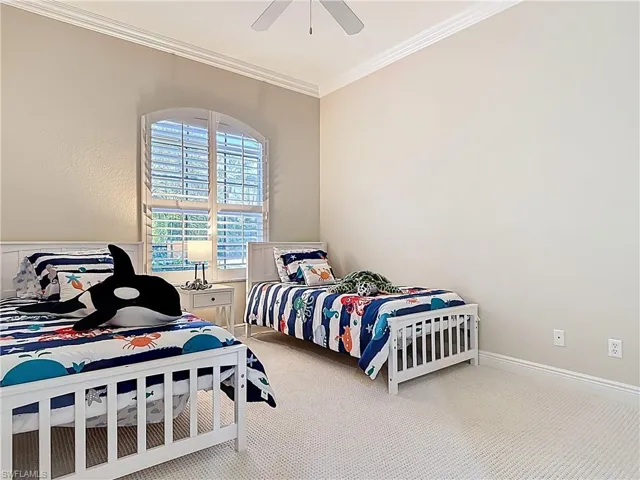 Bedroom with a ceiling fan, newer carpeted floors, and ornamental molding.
