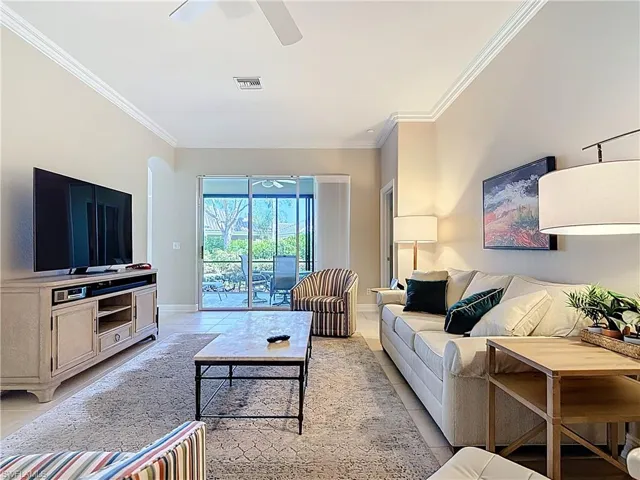 Living area with crown molding, light tile patterned floors and ceiling fan.