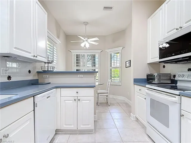 Kitchen featuring white cabinets, white appliances, and decorative backsplash