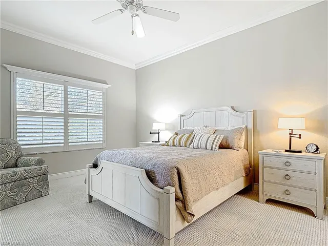 Carpeted bedroom featuring baseboards, crown molding, and a ceiling fan