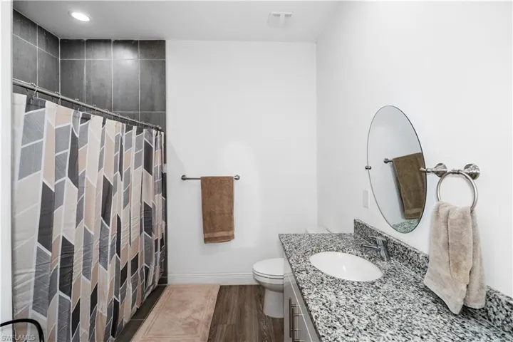 Bathroom with curtained shower, vanity, dark wood-style flooring, and recessed lighting