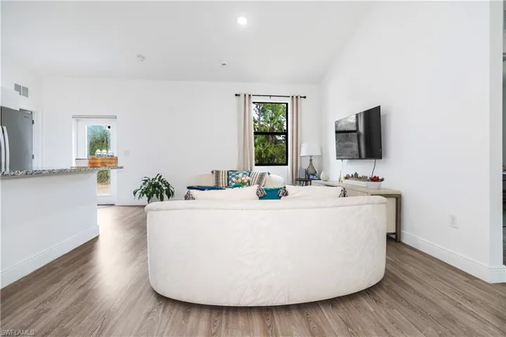 Living room featuring wood finished floors, vaulted ceiling, and recessed lighting