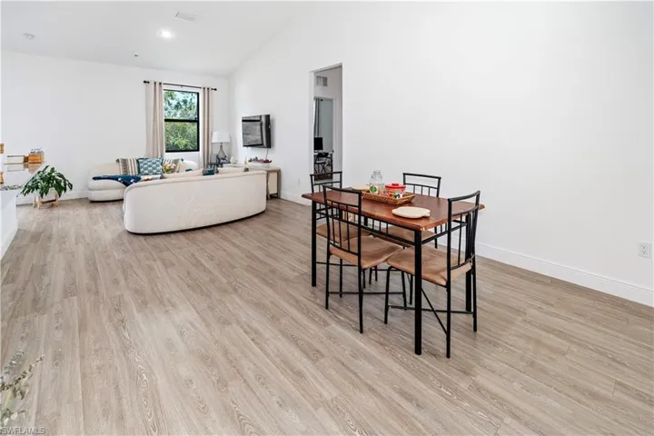 Dining space with light wood-style floors and high vaulted ceiling