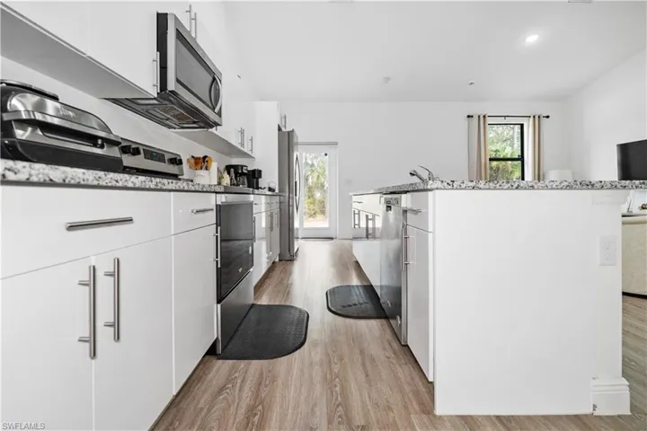 Kitchen featuring white cabinetry, stainless steel appliances, healthy amount of natural light, light wood-style floors, and recessed lighting