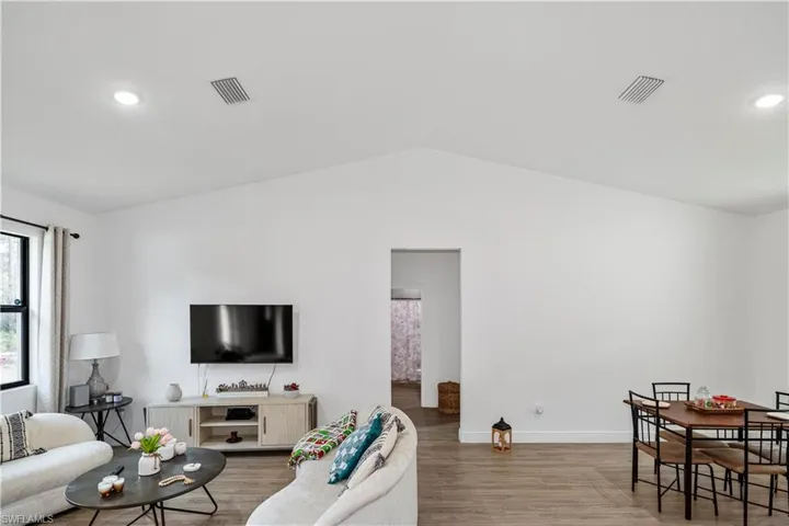 Living room with recessed lighting, lofted ceiling, and light wood-type flooring