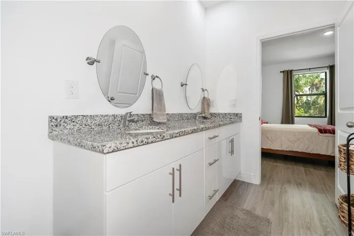 Full bathroom with double vanity, light wood-style floors, ensuite bath, and recessed lighting