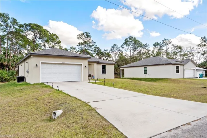 Single story home featuring a front lawn, stucco siding, driveway, and an attached garage