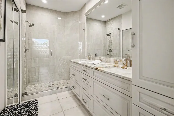Full bathroom with double vanity, a shower stall, light tile patterned floors, and recessed lighting