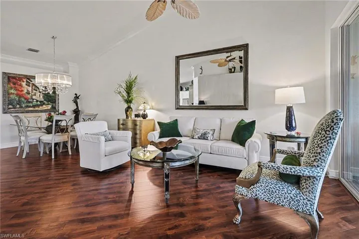 Living room featuring dark wood-style floors, crown molding, and a chandelier