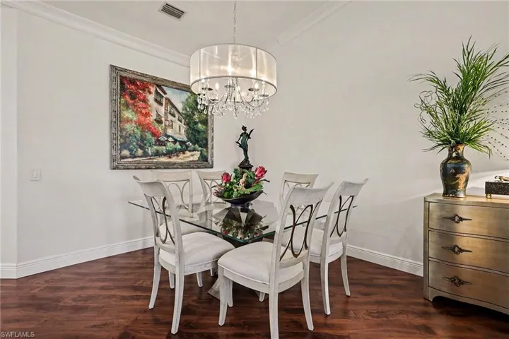 Dining room with dark wood-style floors, crown molding, and a chandelier