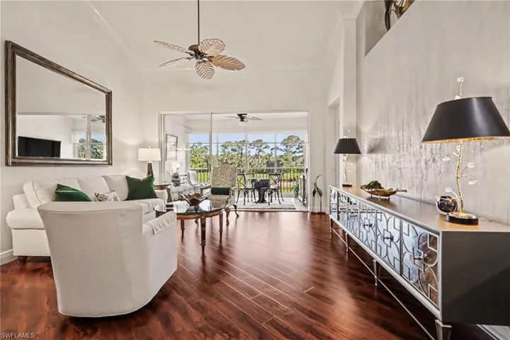 Living area featuring dark wood-style flooring, crown molding, and a ceiling fan