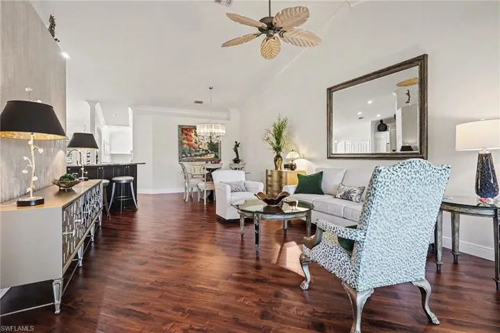 Living room featuring dark wood finished floors, a ceiling fan, vaulted ceiling, recessed lighting, and crown molding