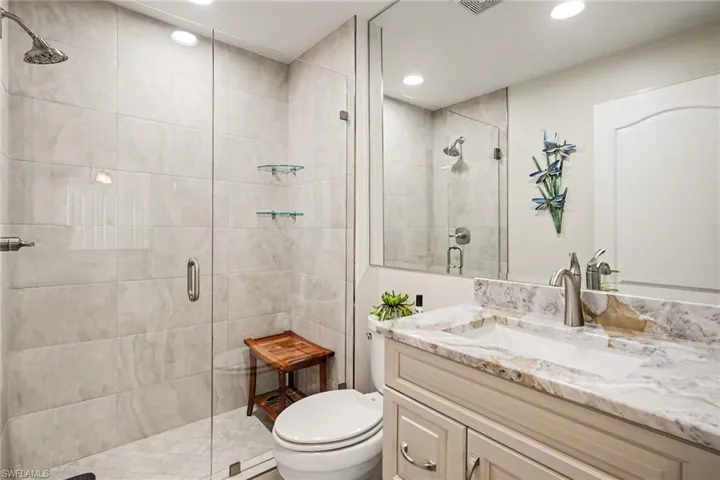 Bathroom featuring a stall shower, vanity, and recessed lighting
