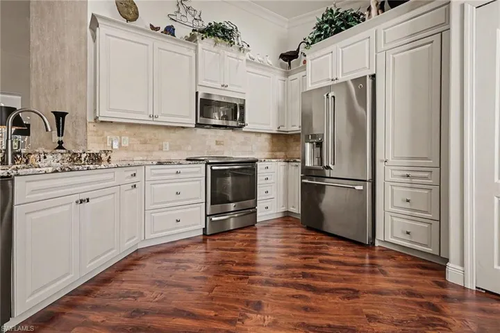 Kitchen with stainless steel appliances, white cabinets, and ornamental molding