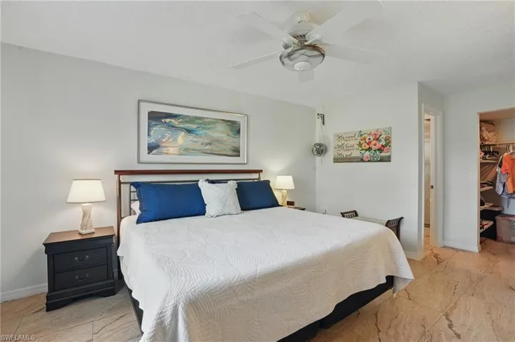 Bedroom with a spacious closet, a closet, baseboards, a ceiling fan, and marble finish floors