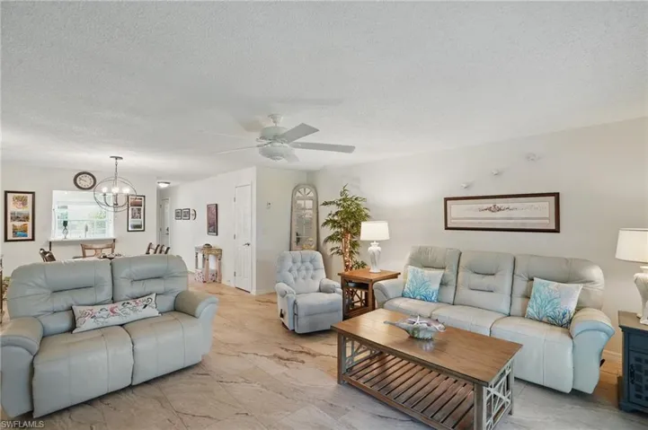 Living room featuring a chandelier, a textured ceiling, and a ceiling fan