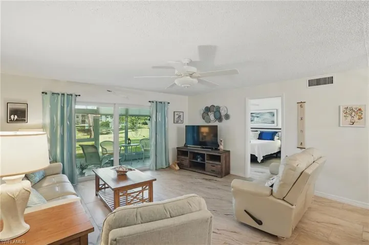 Living area with a ceiling fan, a textured ceiling, and baseboards