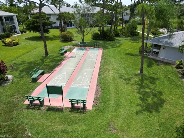 View of community with shuffleboard and a yard